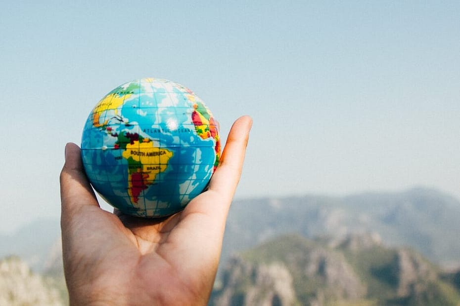 person holding world globe facing mountain